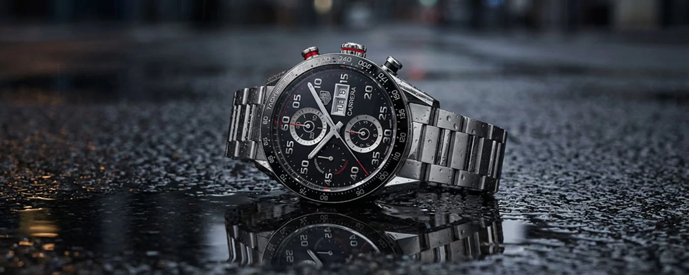 TAG Heuer Carrera Chronograph with black dial and steel bracelet photographed at an angle on dark background with dramatic side lighting