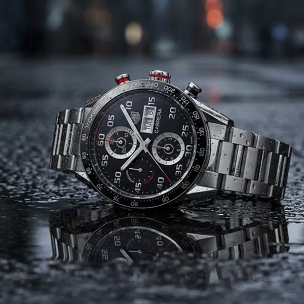 TAG Heuer Carrera Chronograph with black dial and steel bracelet photographed at an angle on dark background with dramatic side lighting