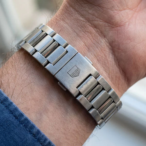 Side profile of TAG Heuer Carrera on a wrist showing the H-link stainless steel bracelet with alternating brushed and polished link surfaces