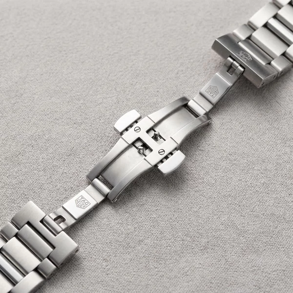 Close-up flat lay of TAG Heuer Carrera open folding clasp showing the double push-button mechanism and solid milled steel interior construction
