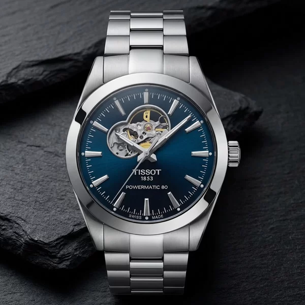 Tissot Gentleman Powermatic 80 Open Heart blue dial stainless steel bracelet watch on dark surface